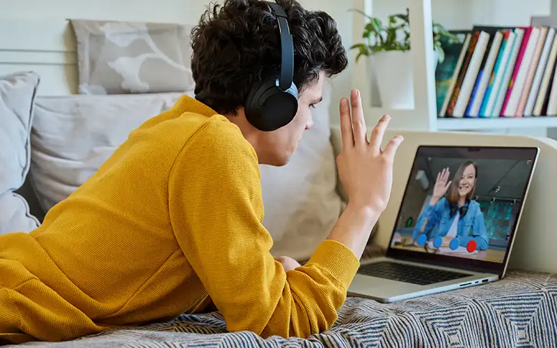 Young guy in a mustard top chatting to his online therapist